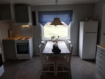 a kitchen with a table with chairs and a window at Leite Gård near Atlantic Road in Hustadvika in Lyngstad