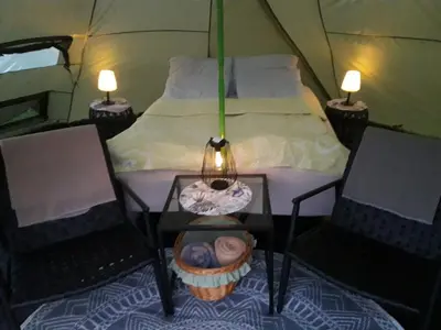 a tent with a bed and two chairs and a table at Leite Gård near Atlantic Road in Hustadvika in Lyngstad