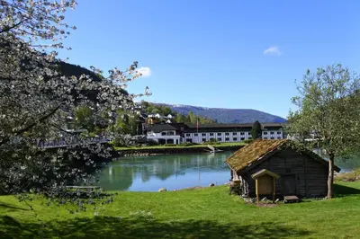 a house on the side of a lake with a building at Stryn Hotel in Stryn