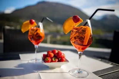 three wine glasses sitting on a table with a bowl of fruit at Stryn Hotel in Stryn