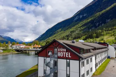 a hotel next to a river and a mountain at Stryn Hotel in Stryn