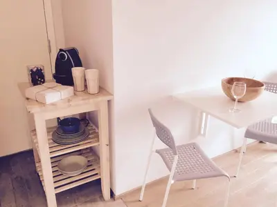 a table and a chair next to a table with plates and a bowl at Knudsen Apartment in Bergen