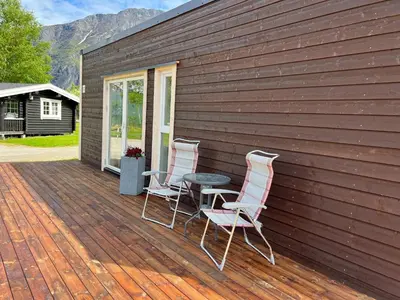 two chairs and a table on a wooden deck at Trollstigen Resort in Åndalsnes