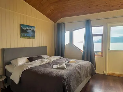 a bedroom with a bed and a large window at Brekkestranda Fjordhotel in Brekke