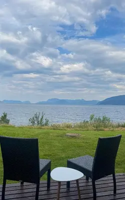 two chairs and a table on a deck overlooking the water at Brekkestranda Fjordhotel in Brekke