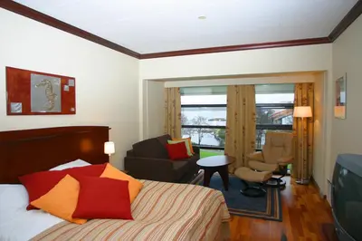 a bedroom with a bed and a living room at Fitjar Fjordhotell in Fitjar