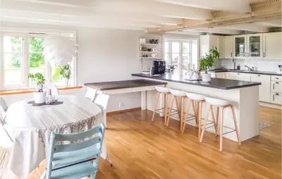 a kitchen with white cabinets and a table with stools at Lovely Home In Valevåg With Wifi in Valevåg