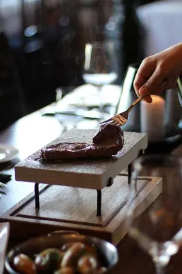 a person cutting a piece of meat on a cutting board at Oppdal Turisthotell in Oppdal