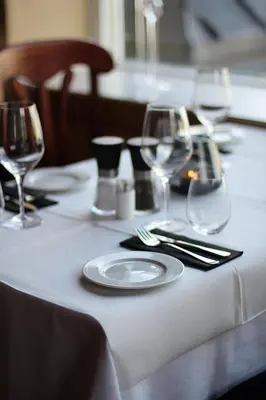a table with a white table cloth with wine glasses at Oppdal Turisthotell in Oppdal