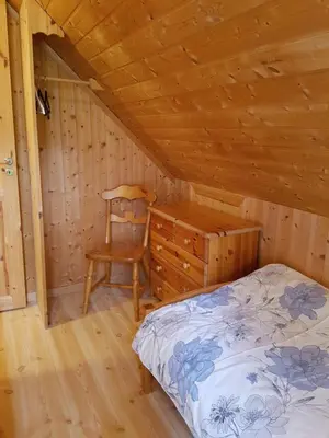 a bedroom with a bed and a chair in a cabin at Rugsund Handelsstad in Rugsund