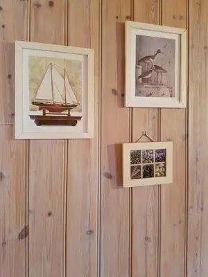 three pictures are hanging on a wooden wall at Rugsund Handelsstad in Rugsund
