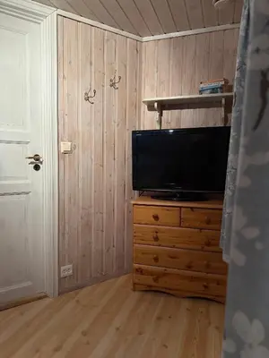 a living room with a television on a wooden dresser at Rugsund Handelsstad in Rugsund