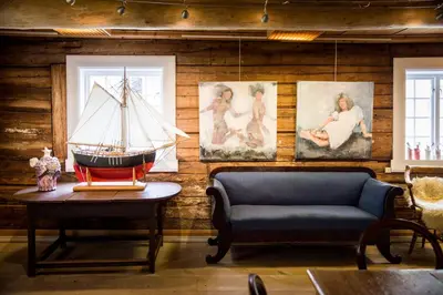 a living room with a boat on a table and paintings at Walaker Hotel in Solvorn