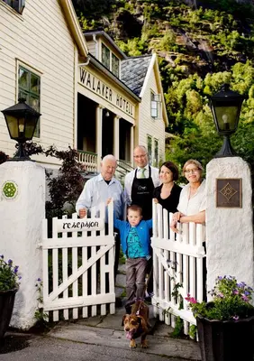 a family posing in front of a white fence at Walaker Hotel in Solvorn