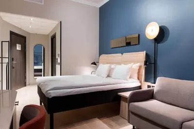 a bedroom with a bed and a couch and a chair at Scandic Torget Bergen in Bergen