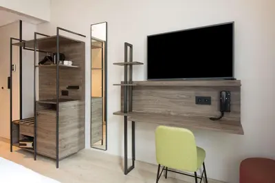 a room with a tv and a chair and a mirror at Scandic Torget Bergen in Bergen