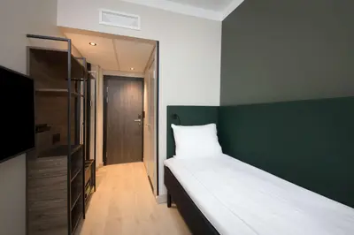 a bedroom with a bed and a green wall at Scandic Torget Bergen in Bergen