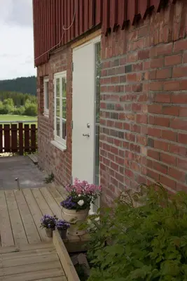 a brick building with a white door and flowers on a porch at Munkeby Herberge in Levanger