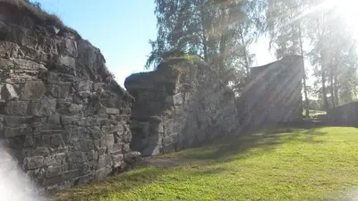 an old stone wall with a grass field next to it at Munkeby Herberge in Levanger