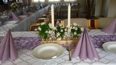 a long table with white plates and purple napkins and flowers at Munkeby Herberge in Levanger