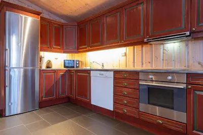 a kitchen with wooden cabinets and a stainless steel refrigerator at Knuts Hyttegrend in Beitostøl