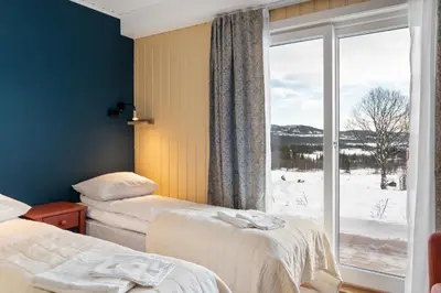 a room with two beds and a large window at Grønolen Fjellgard in Beitostøl