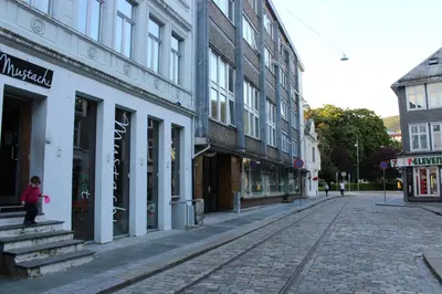 an empty city street with buildings and a girl standing in the street at MB Apartments in Bergen