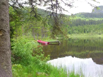 a red boat sitting on a lake in the woods at Leilighet i Åmotsdal in Åmotsdal