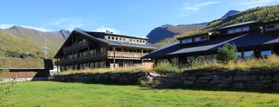 a large building with mountains in the background at Blåtind Apartments in Stordal