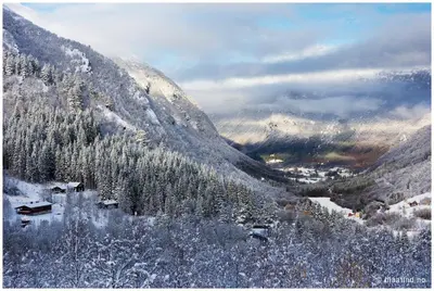 a snow covered mountain with a village in the foreground at Blåtind Apartments in Stordal