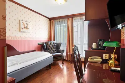 a bedroom with a bed and a chair and a window at Best Western Laegreid Hotell in Sogndal