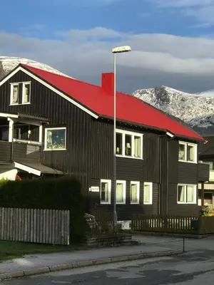 a house with a red roof with mountains in the background at Villa Åndalsnes in Åndalsnes