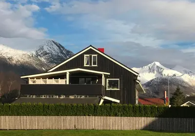 a black house with snow covered mountains in the background at Villa Åndalsnes in Åndalsnes