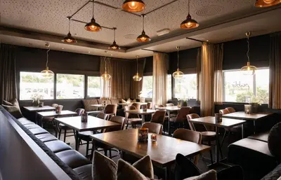 a restaurant with tables and chairs and windows at Ågotnes Motell in Ågotnes