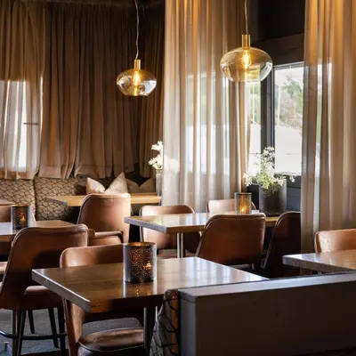 a dining room with tables and chairs and lights at Ågotnes Motell in Ågotnes