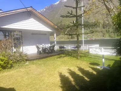 a patio with a table and chairs in a yard at Der Fjordtraum in Balestrand direkt am Wasser in Balestrand
