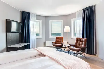 a bedroom with a bed and two chairs and a television at Quality Hotel Ålesund in Ålesund