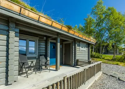 a wooden cabin with a porch with a table and chairs at Gladheim in Stranda