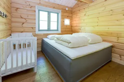 a bedroom with a crib in a wooden cabin at Gladheim in Stranda