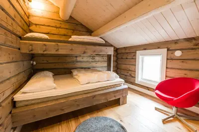 a log cabin bedroom with a bed and a red chair at Lake View Apartment 4 bedrooms in Brunstad