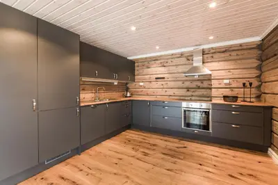 a kitchen with gray cabinets and wooden walls at Lake View Apartment 4 bedrooms in Brunstad