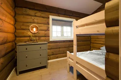 a bedroom with wooden walls and a bed and a window at Strandafjellet Mountain Lodge in Stranda