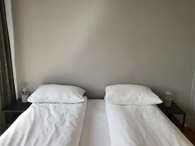 two beds in a room with white sheets and pillows at Veversmauet Apartments in Bergen