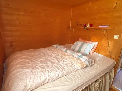 a bed in a room with a wooden wall at Haukeli Mountain Cabin in Vågsli