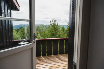 an open door to a balcony with a view of the mountains at Putten Seter in Høvringen