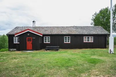 a black house with a red door and a bench at Putten Seter in Høvringen