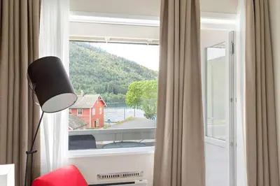 a room with a large window with a red house at Kinsarvik Fjordhotel, BW Signature Collection in Kinsarvik