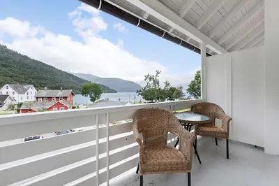 a balcony with chairs and a table and a view of the water at Kinsarvik Fjordhotel, BW Signature Collection in Kinsarvik