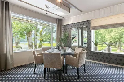 a dining room with a table and chairs and windows at Kinsarvik Fjordhotel, BW Signature Collection in Kinsarvik