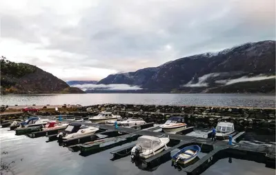 a group of boats docked at a dock on a lake at 3 Bedroom Nice Home In Vallavik in Vangsbygd